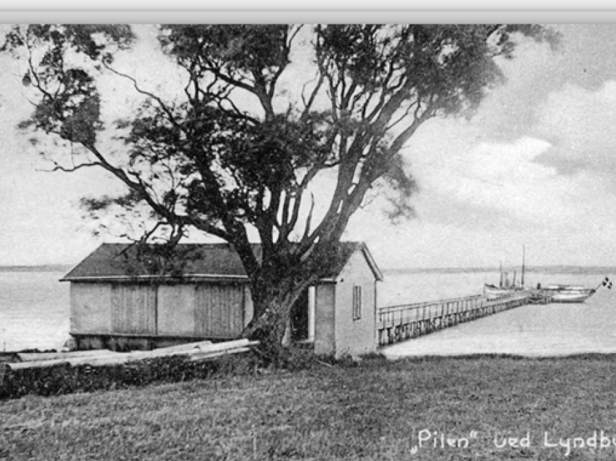 Pakhus og Pilen for enden af anløbsbroen i 1908. Postkort. Foto: Erh. Flensborg, Roskilde Kilde: https://arkiv.dk/vis/4021241 